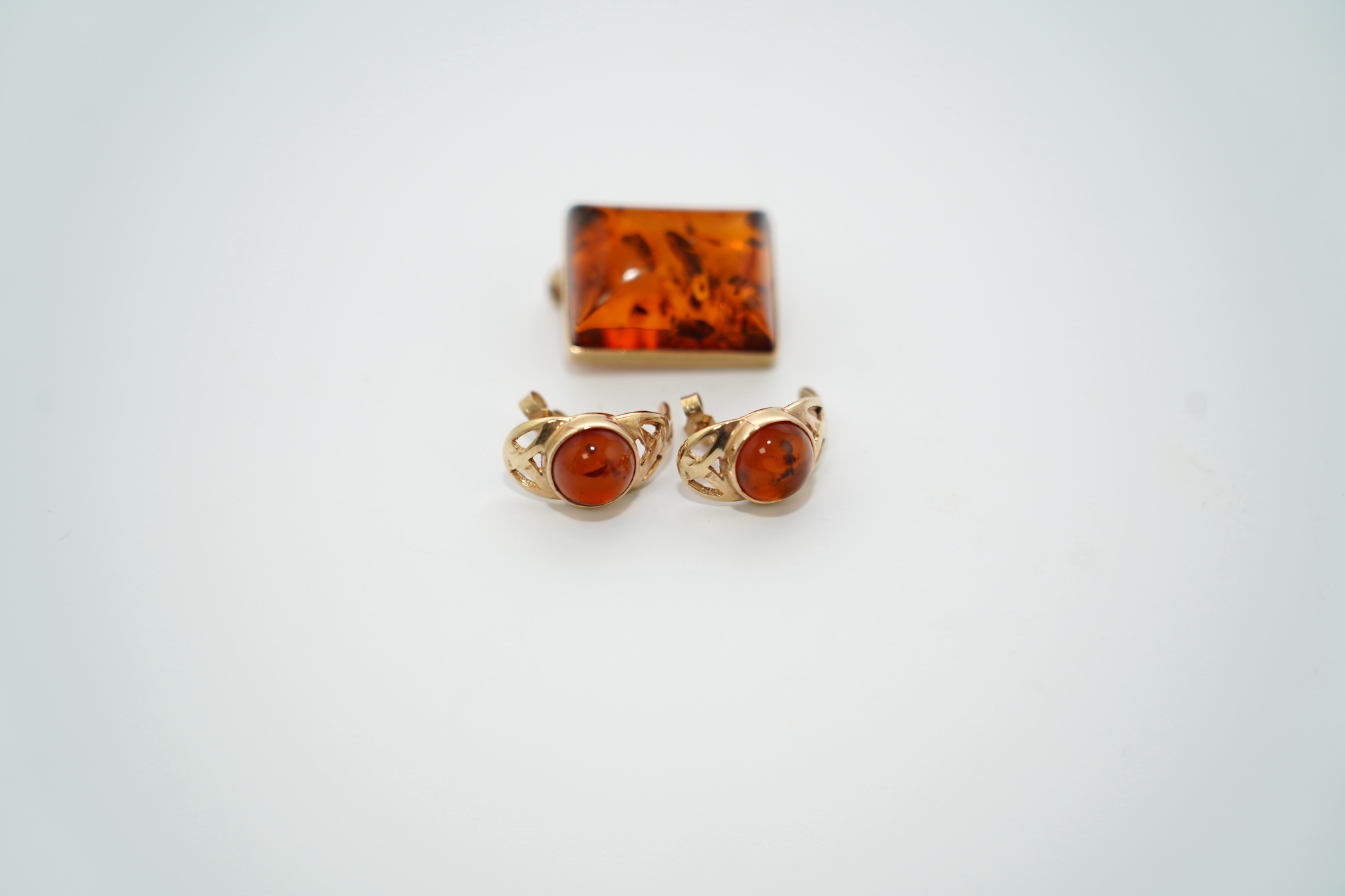 A modern pair of 9ct gold and amber set earrings and a 9ct gold mounted amber brooch, 19mm, gross weight 7.3 grams. Condition - good